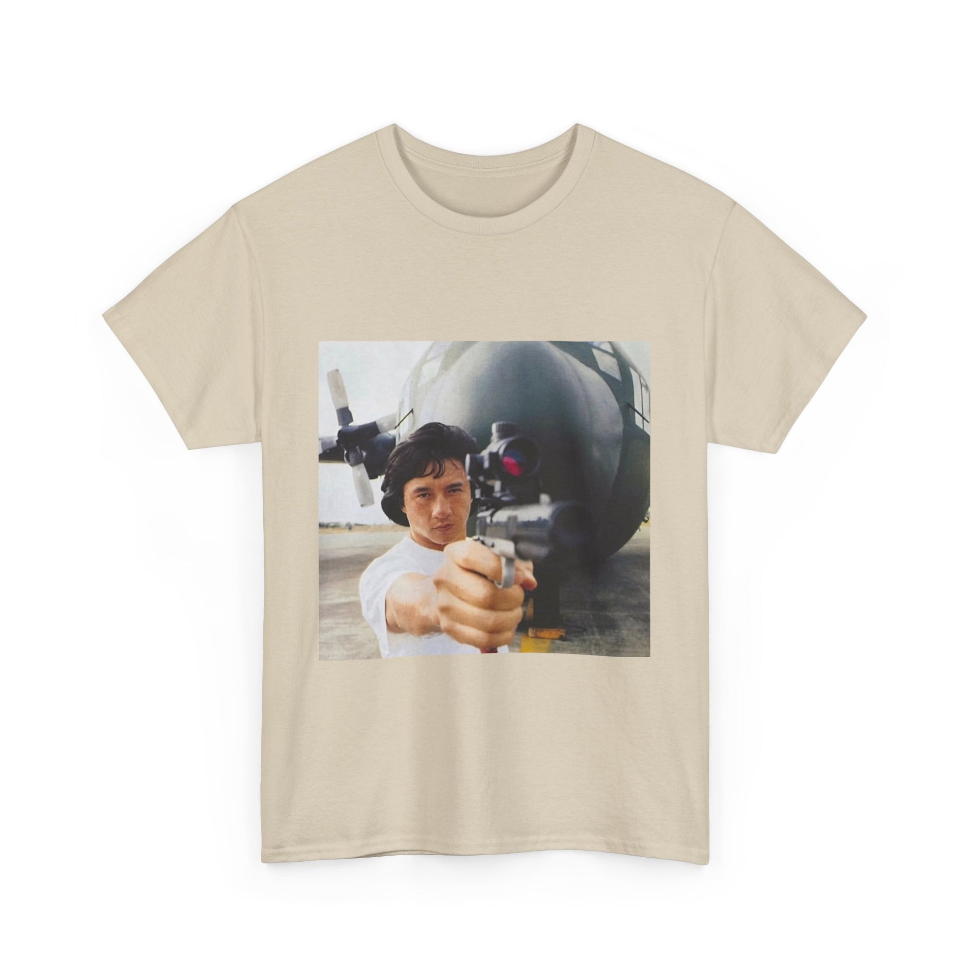 Beige t-shirt with a graphic of a person holding a gun in front of an airplane.