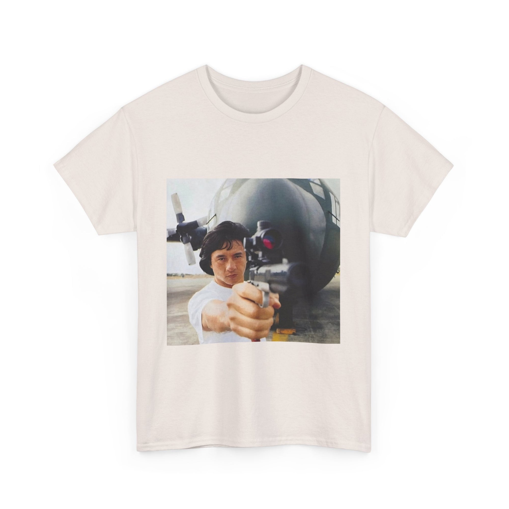 Beige t-shirt with a graphic of a person holding a gun in front of an airplane.
